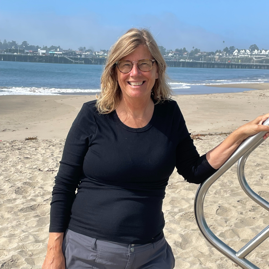 Sonja Brown standing on a beach with ocean and skyline in the background