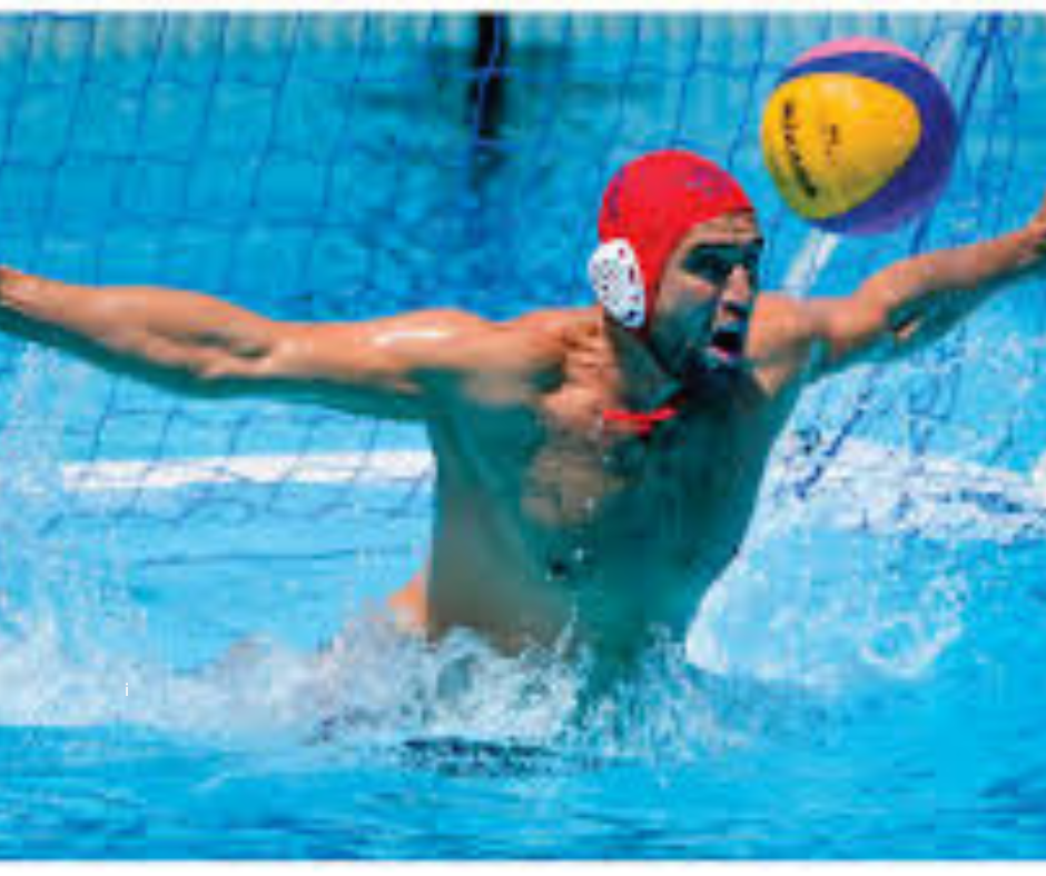 Adult male water polo goalie is in action with a ball heading right for his head in a swimming pool. He has a Hammer Head swimcap under his water polo cap for extra head protection to avoid or minimize head injuries.