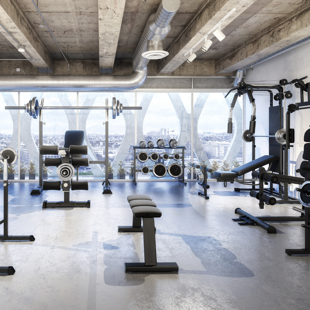Modern gym interior with various exercise equipment and large windows.
