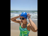 This Asian female open water swimmer and triathlete demonstrates how to put on Hammer Head if you have long hair. She is wearing the blue Hammer Head Swim Caps - Safe and Fast Swim Cap for Adults and Youth, 50% Safer and 10.5% Faster than Standard Swim Caps, Durable with 365-Day Guarantee, Approved by Olympians, Parents, Triathletes, and Coaches. Hammerhead swim caps is a waterproof swim cap, qualifies for custom swim caps with three size options and is perfect for ironman swim caps. 