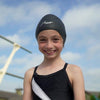 Young girl swimmer is wearing a black Hammer Head swim cap at the swimming pool. It is the best swim cap technology and is a great swim cap for small heads.